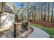 Landscaped side yard featuring stone pillars, an iron fence, and a walkway leading to the wooded area at 8170 Hurakan Creek Xing, Cumming, GA 30028