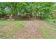 Landscaped backyard featuring grass, scattered trees, and natural foliage at 162 Riverchase Dr, Woodstock, GA 30188