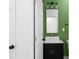 Bathroom featuring modern vanity, mirror, and lighting with green accent wall at 4219 David Austin Ct, Snellville, GA 30039