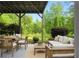 An outdoor covered patio features a dining set and a seating area surrounded by lush green landscaping at 4219 David Austin Ct, Snellville, GA 30039