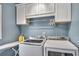 Convenient laundry room includes front-load washer and dryer, storage cabinets, and an ironing board at 225 Ruby Forest Pkwy, Suwanee, GA 30024