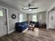 Inviting living room features a comfortable, blue sectional sofa, modern ceiling fan, and bright natural light at 6567 Post Rd, Douglasville, GA 30135