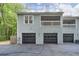 Exterior view of townhouse featuring a three-car garage with a covered balcony above at 701 Dunwoody Chace, Atlanta, GA 30328