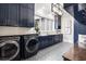 Well-lit laundry room features a washer, dryer, patterned floor, sink, and dark blue cabinets at 1445 Hillside Dr, Grayson, GA 30017
