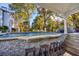 Luxurious poolside bar area with seating, granite countertops, and a view of the stunning pool and lush landscaping at 1445 Hillside Dr, Grayson, GA 30017