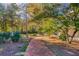 Charming brick walkway through a landscaped yard with mature trees and lush foliage at 1445 Hillside Dr, Grayson, GA 30017