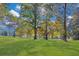 Lush green lawn surrounded by trees, with dappled sunlight filtering through the branches at 1445 Hillside Dr, Grayson, GA 30017