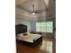 Spacious main bedroom featuring a tray ceiling, a ceiling fan, hardwood floors, and a large window at 320 Orleans Blvd, Mcdonough, GA 30253