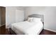 A simple bedroom with dark wood floors, a gray upholstered bed frame, and a closet at 4766 Longcourt Se Dr # 23, Atlanta, GA 30339