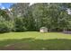 Large backyard features a shed for storage, grassy lawn, chain link fence, and mature trees at 510 Pineland Sw Rd, Mableton, GA 30126