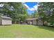 Wide backyard view of a tan one-story home, storage shed, wooden deck, lawn, and mature trees at 510 Pineland Sw Rd, Mableton, GA 30126
