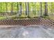 Landscaped backyard with brick retaining wall and tall, mature trees at 5335 Lexington View Pl, Sugar Hill, GA 30518