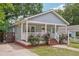 Inviting home with a covered front porch, blooming rose bushes, and a side entrance with stairs at 789 Third St, Stone Mountain, GA 30083