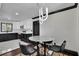 Dining area with modern light fixture next to kitchen with white cabinets and dark appliances at 1722 San Gabriel Ave, Decatur, GA 30032
