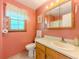 A bathroom features a window, sink, and toilet with light pink walls at 70 Heritage Way, Covington, GA 30016