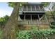 Low angle of a backyard with greenery, a retaining wall, and a two-story deck with a screened-in porch at 1066 High Point Ne Dr, Atlanta, GA 30306