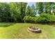 Grassy backyard with stone fire pit surrounded by mature trees at 1652 Weymouth Ct, Tucker, GA 30084