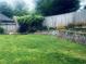 Lush backyard with a large lawn, wooden fence, landscaping, and hardscape retaining wall at 2945 Dogwood Creek Parkway, Duluth, GA 30096
