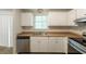 Well-lit kitchen featuring white cabinets, stainless steel dishwasher, and wood look flooring at 5372 Martins Crossing Rd, Stone Mountain, GA 30088