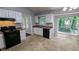 Bright kitchen with white cabinets, black appliances, and views of the backyard through large windows at 4827 Wyndam Dr, Stone Mountain, GA 30088