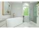 This bright bathroom features a standalone tub, glass-enclosed shower, and mosaic-patterned walls at 341 Lands Se Ml, Marietta, GA 30067