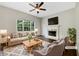 Cozy living room featuring a fireplace, ceiling fan, and large window overlooking the backyard at 617 Kyles Cir, Hiram, GA 30141