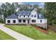 Beautiful white two-story home with a manicured lawn, black shutters, and a brick foundation at 7620 Breeze Bay Rd, Cumming, GA 30041