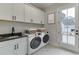 Well-equipped laundry room with sleek cabinets, granite counters, sink, and modern washer and dryer at 7620 Breeze Bay Rd, Cumming, GA 30041
