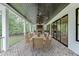 Covered patio with brick flooring features an outdoor table and seating with a fireplace and ceiling fans at 7620 Breeze Bay Rd, Cumming, GA 30041