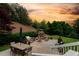 Backyard patio with an outdoor kitchen, dining table, chairs, and fireplace at sunset at 2020 Windermere Xing, Cumming, GA 30041