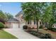 Two-story brick home featuring an attached three-car garage and meticulously landscaped yard at 2020 Windermere Xing, Cumming, GA 30041