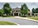 Traditional-style home with a lush front yard, mature trees, and a circular driveway at 2020 Windermere Xing, Cumming, GA 30041
