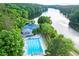 Aerial view of a large community pool, tennis court, and clubhouse surrounded by green trees on the lake at 525 Watergate Ct, Roswell, GA 30076