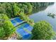 Aerial view of two blue tennis courts near a lake and surrounded by lush green trees and foliage at 525 Watergate Ct, Roswell, GA 30076