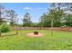 Spacious backyard featuring a fire pit, green grass, and tall trees beyond the wooden fence at 159 Cranbrooke Dr, Dallas, GA 30157