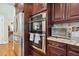 Close up of the kitchen featuring stainless steel oven, toaster oven, and refrigerator surrounded by rich, dark wood cabinetry at 2460 Due West Nw Cir, Kennesaw, GA 30152