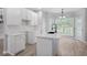 Bright kitchen boasts white cabinets, an island with quartz countertop, and hardwood flooring at 463 The Gables Dr, Mcdonough, GA 30253