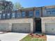 Stylish townhome showing the brick front, two-car garage, landscaping, and neutral exterior colors at 1406 Lucan Nw Ln # Wc221, Lawrenceville, GA 30043