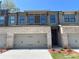 Charming townhome featuring a two-car garage, brick accents, and a welcoming teal front door at 1406 Lucan Nw Ln # Wc221, Lawrenceville, GA 30043