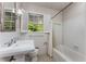 Bright bathroom features a white sink, toilet, and bathtub with shower, plus a window with garden views at 2517 Birchwood Ne Dr, Atlanta, GA 30305