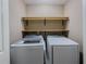 Bright laundry room featuring modern washer and dryer with wooden storage shelves at 3318 Sardis Bend Dr, Buford, GA 30519