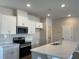 Bright kitchen with stainless steel appliances, white cabinets, tile backsplash, and a countertop island with a sink at 2335 Portrush Way (Lot 26) Dr, Atlanta, GA 30339