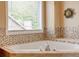 Bathroom with soaking tub, stone-look tile, and large window at 133 Parkway Dr, Fairburn, GA 30213