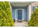 Classic blue front door framed by lush greenery and brick accents, creating a welcoming entrance at 133 Parkway Dr, Fairburn, GA 30213