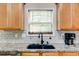 Well-appointed kitchen sink area with granite countertops, tile backsplash, and wood cabinets offering functional style and storage at 133 Parkway Dr, Fairburn, GA 30213