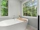 Modern bathroom featuring a freestanding tub by a window with nature views, creating a relaxing spa-like atmosphere at 4504 Reva Ne Way, Marietta, GA 30066