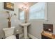 Bathroom with pedestal sink, toilet, decorative mirror, and natural light at 218 Ward Rd, Ellenwood, GA 30294