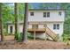 Back exterior view of the home featuring a deck, stairs, and lush trees surrounding the property at 1489 Kolb Ridge Sw Dr, Marietta, GA 30008
