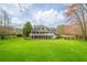 Expansive backyard featuring lush green lawn, mature trees, and a rustic fence at 210 Little River Farms Trl, Canton, GA 30115