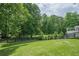 Green backyard with mature trees and a wooden fence in the background at 210 Little River Farms Trl, Canton, GA 30115